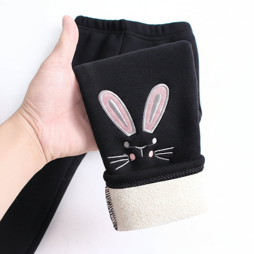 Black leggings with a rabbit design held by a hand on a white background