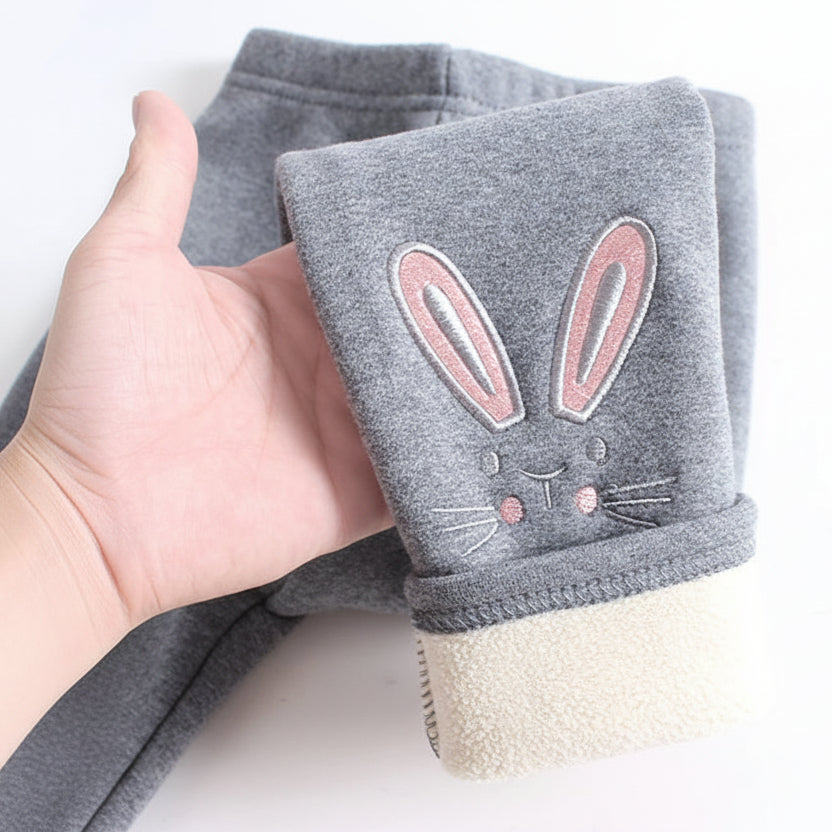 Gray baby leggings with bunny design held by a hand on a white background