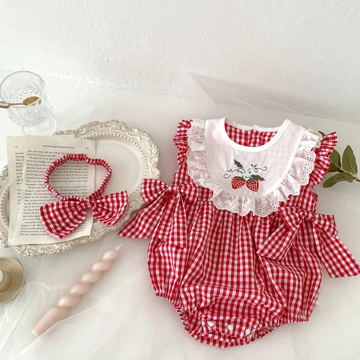 Red and white checkered baby romper with ruffles on a white surface