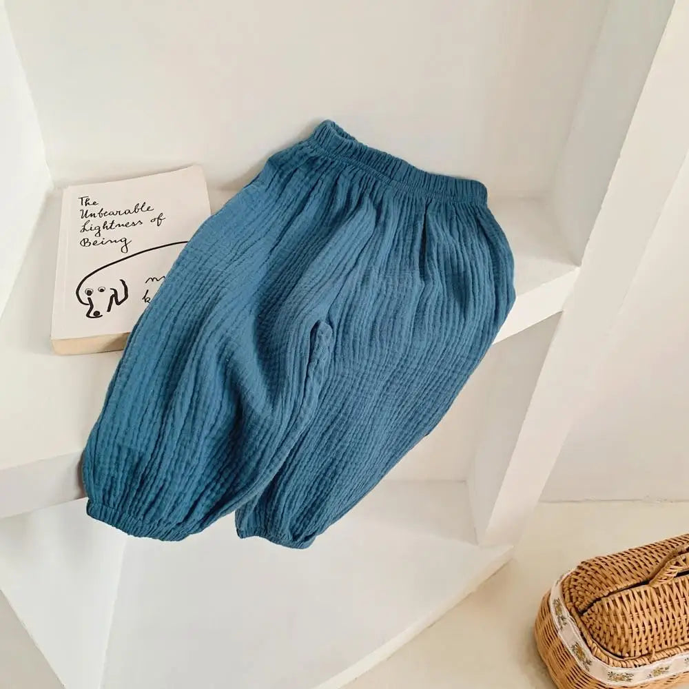 Blue baby bloomers on a white surface with a book and woven basket in the background