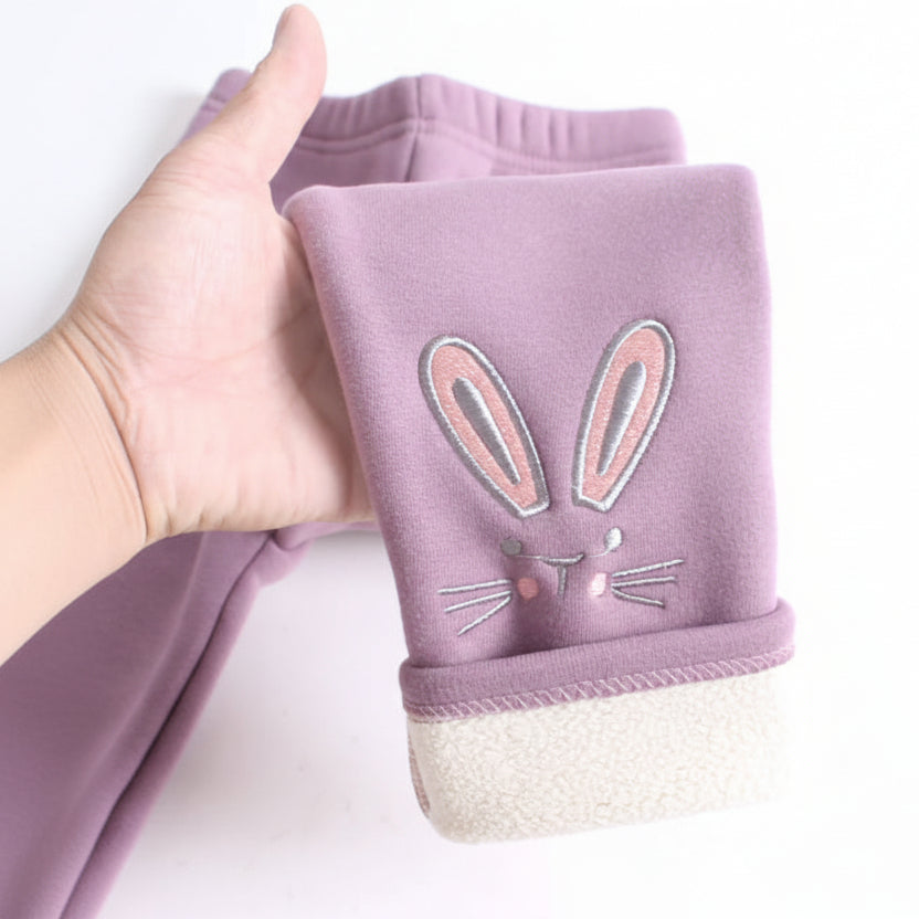 Purple baby leggings with bunny design held by a hand on a white background