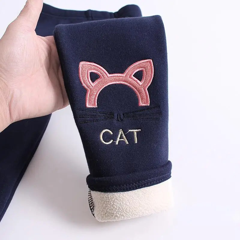 Navy blue pet coat with cat-themed design held by a hand on a white background