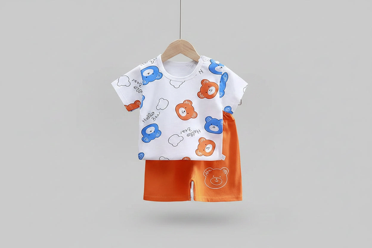 Baby outfit with cartoon bear print shirt and orange shorts on a hanger against a dark background.