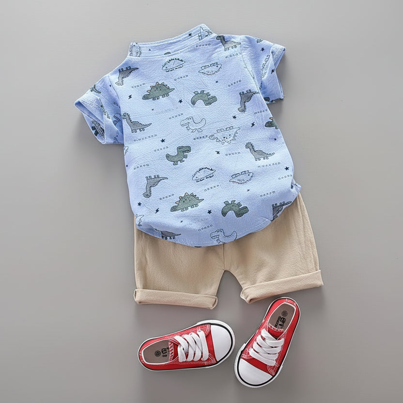 Children's outfit with blue t-shirt and beige shorts, red sneakers, and a toy camera on a gray surface.