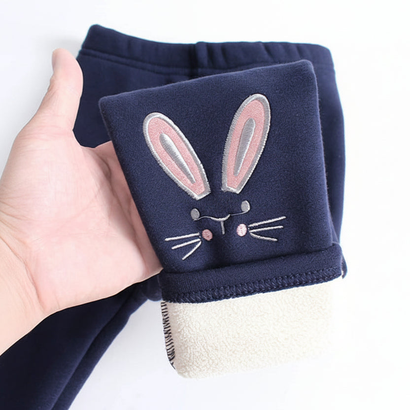 Navy blue fabric with a bunny face design held by a hand on a white background.